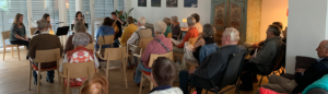 Eine Gruppe von Rentnerinnen und Rentner bei einem Wohnzimmerkonzert.