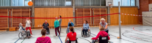 Eine Gruppe von Menschen, die im Rollstuhl sitzen und zusammen mit einem Ball spielen.