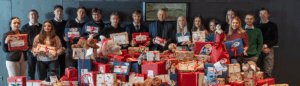 Die Auszubildenden der Sparkasse Rosenheim-Bad Aibling mit Karl Göpfert und Alexa Dietz vor einem Tisch voller eingepackter Geschenke.