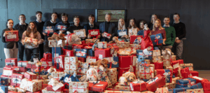 Die Auszubildenden der Sparkasse Rosenheim-Bad Aibling mit Karl Göpfert und Alexa Dietz vor einem Tisch voller eingepackter Geschenke.