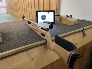 „Blick auf einen Schießstand mit Gewehr und elektronischer Trefferanzeige auf einem Bildschirm.“